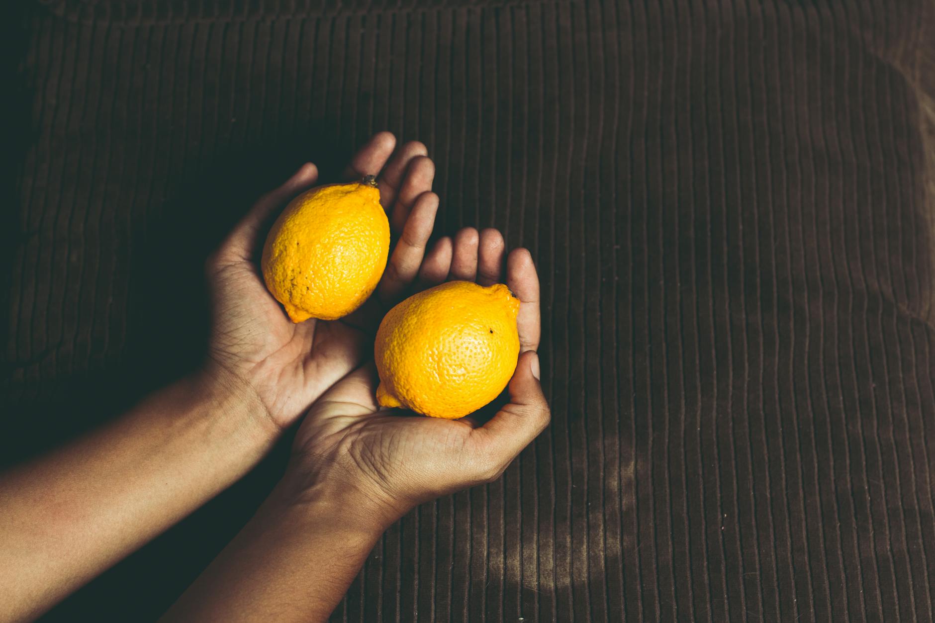 Two fresh lemons held in cupped hands, symbolizing care and gentle recovery