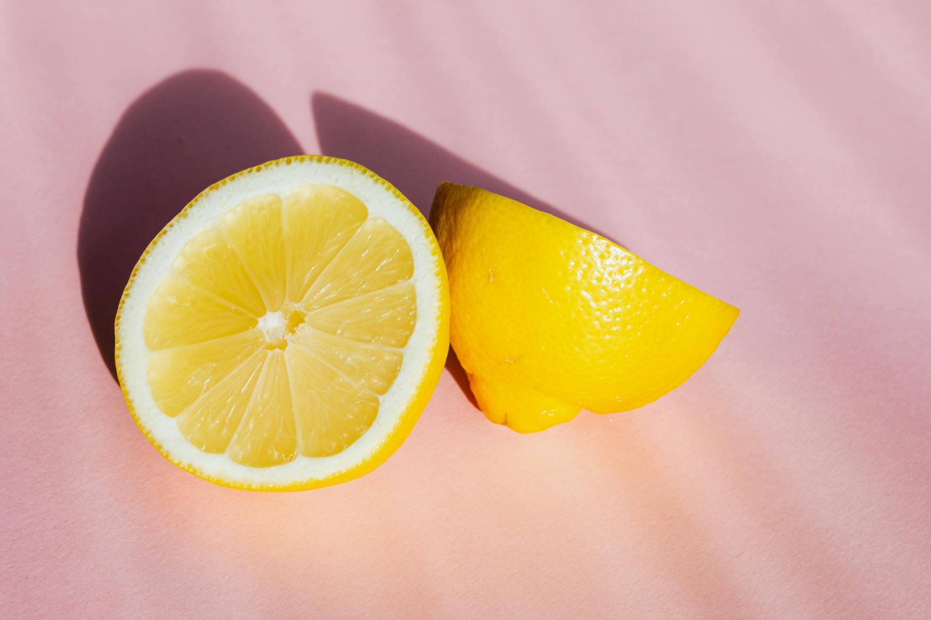 Fresh lemon halves on a pink background symbolizing gentle, refreshing pleasure