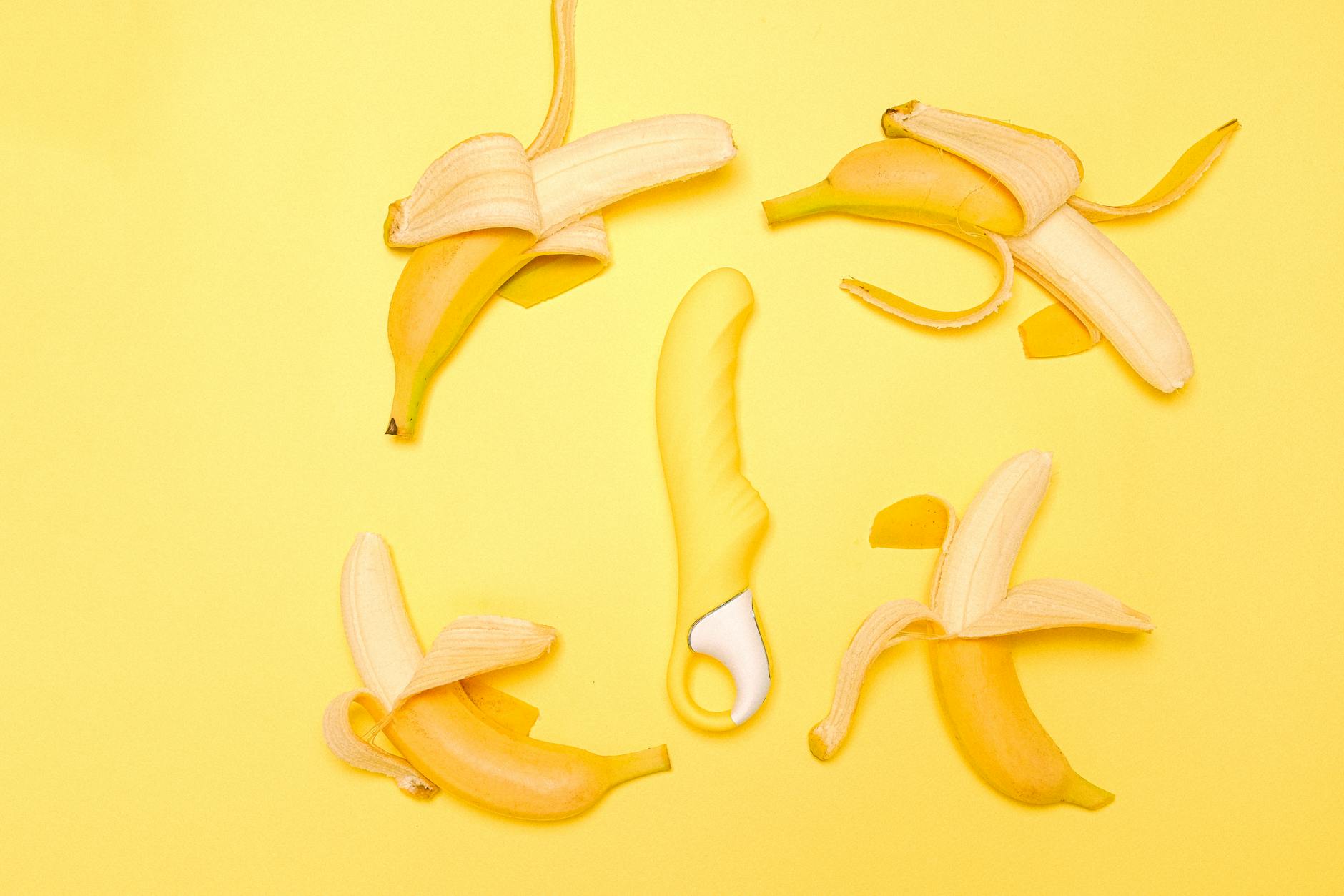 Yellow silicone lemon clitoral vibrator on a bright yellow background surrounded by fresh fruit