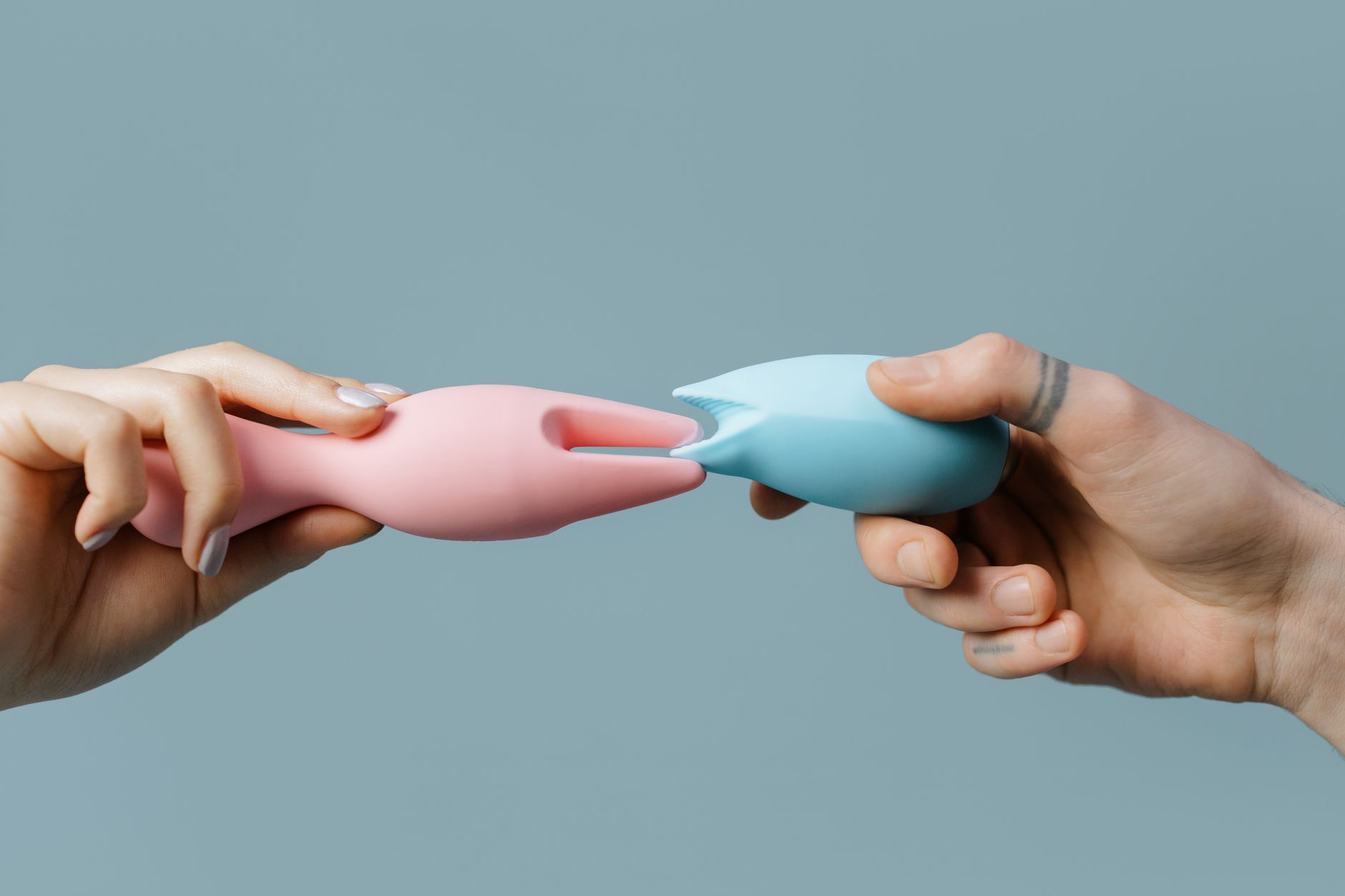 Close-up of a hand holding an orange vibrator against a minimalist purple backdrop