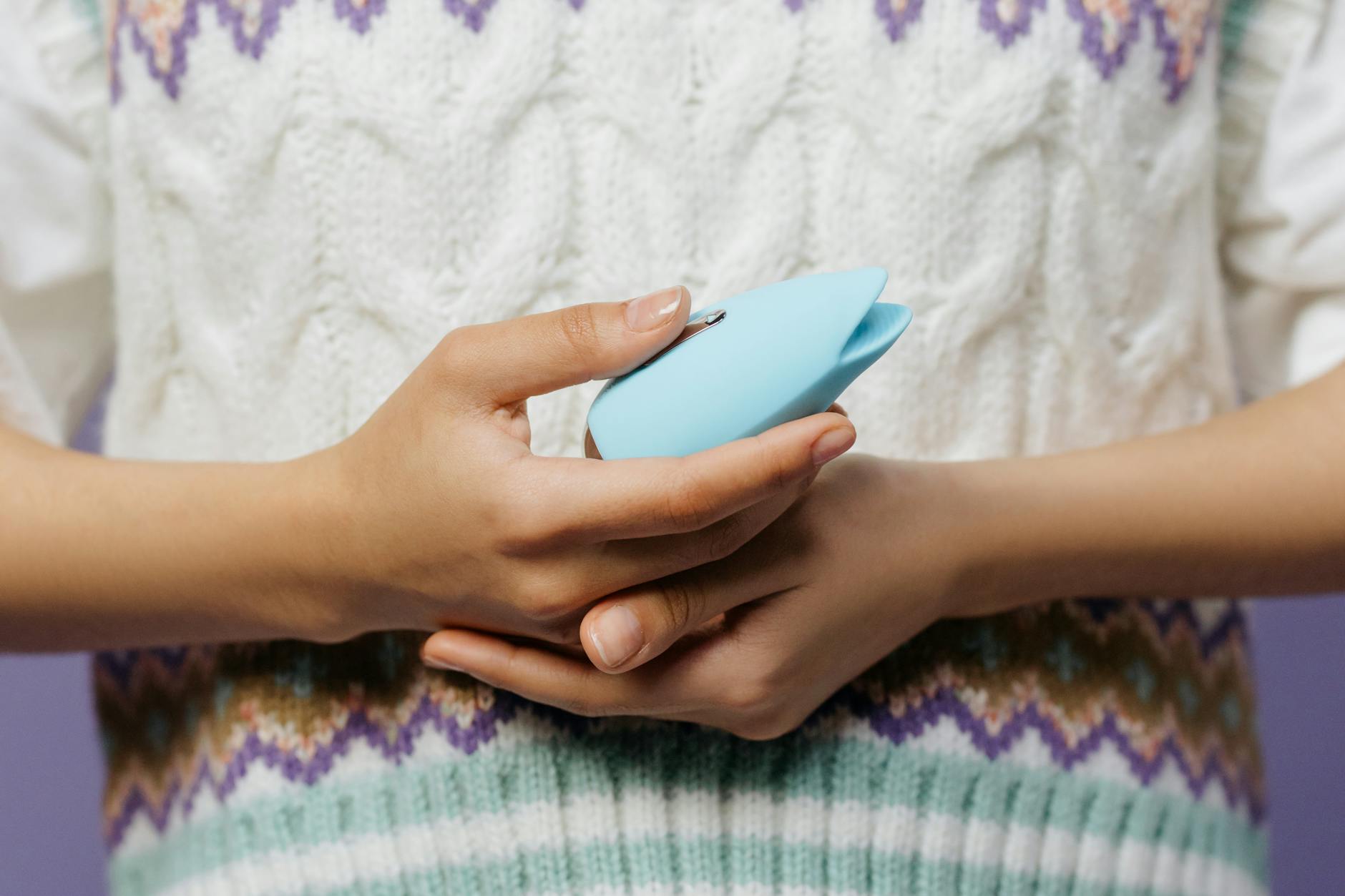 A young couple standing together indoors, holding a blue vibrator, symbolizing modern intimacy and partnership.
