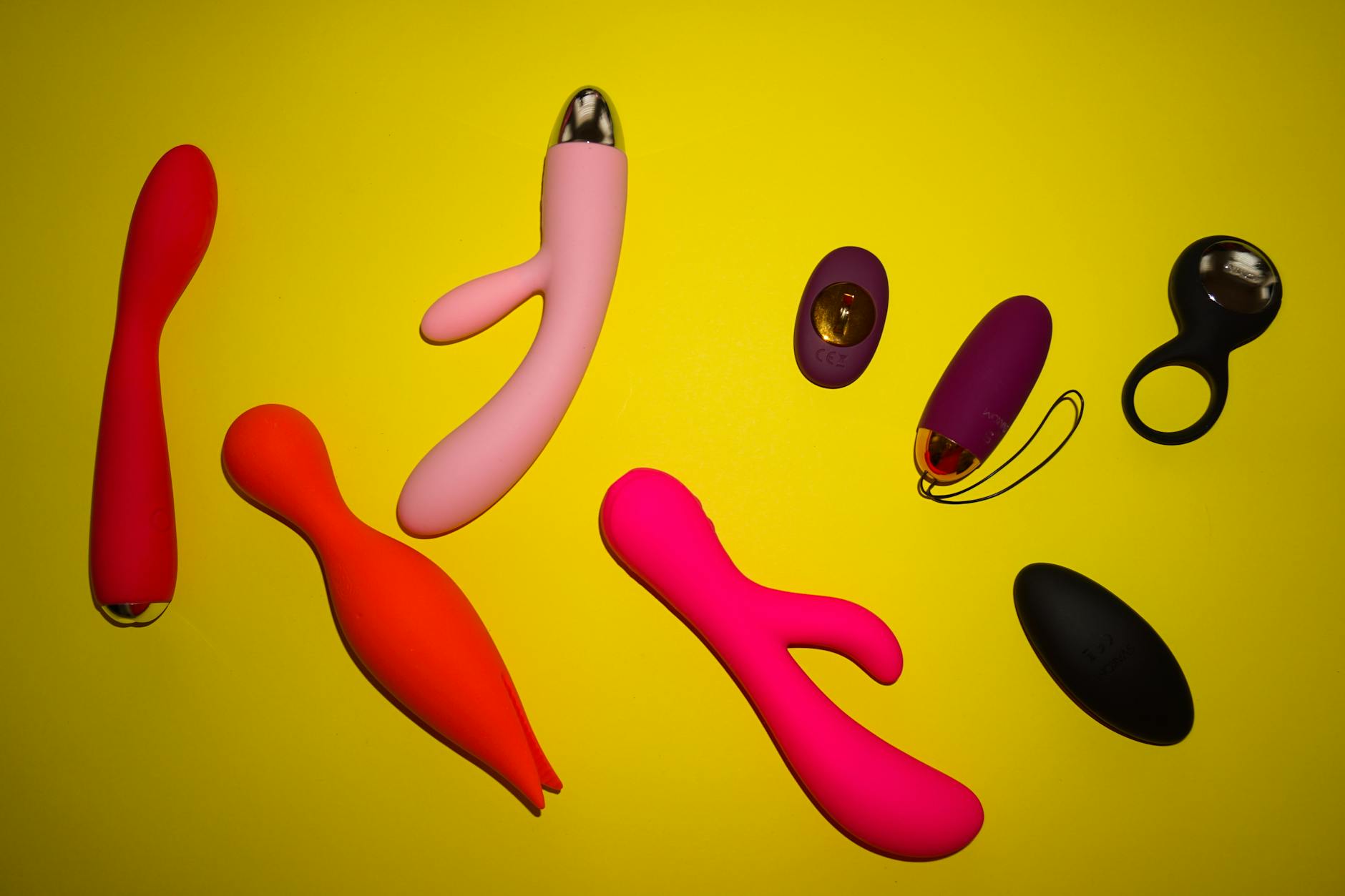 Blue vibrator surrounded by flowers and citrus on a bright yellow background, symbolizing renewal and pleasure restoration