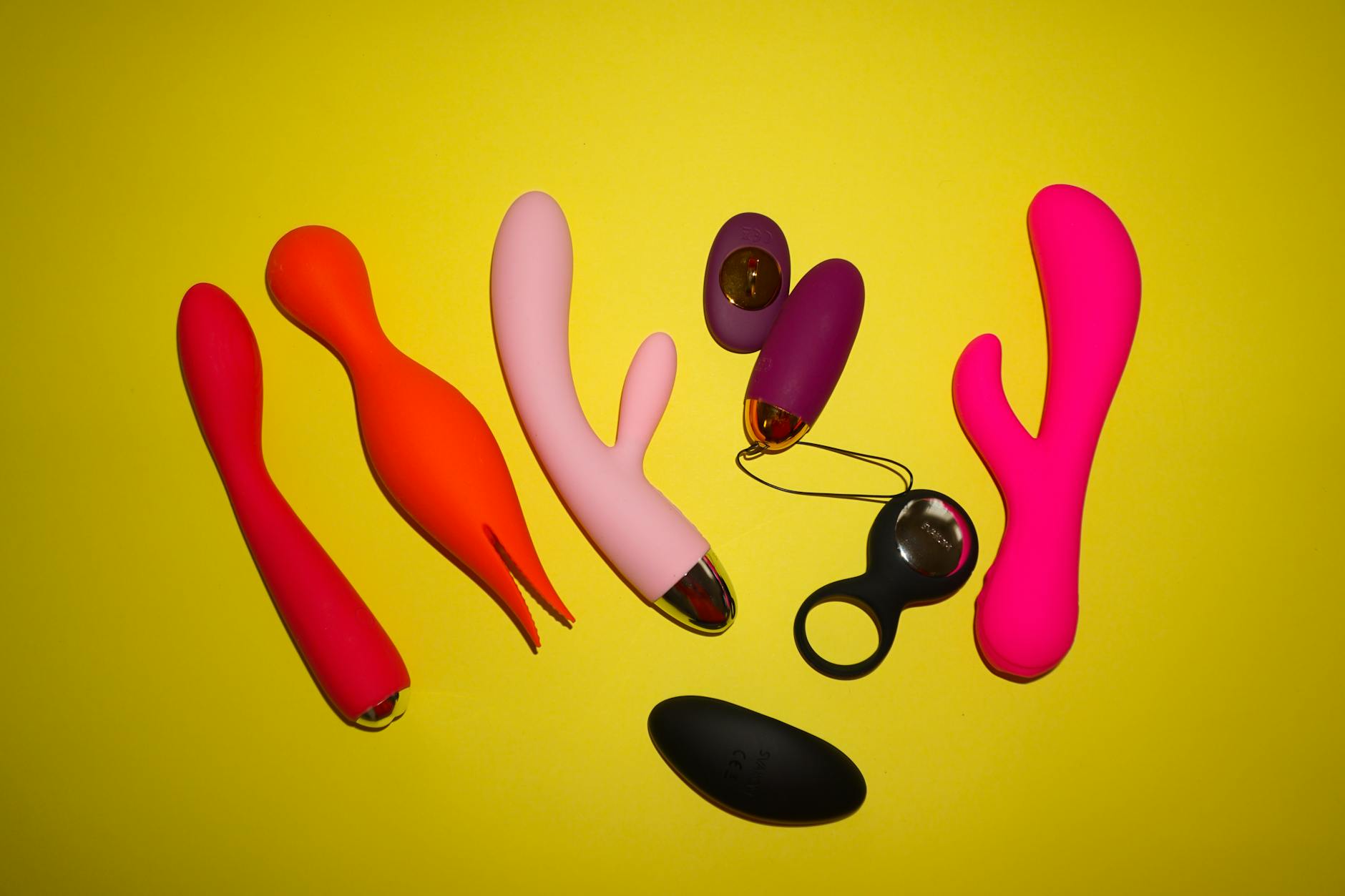 Colorful lemon vibrators and sexual toys arranged on a bright yellow background in a studio setting