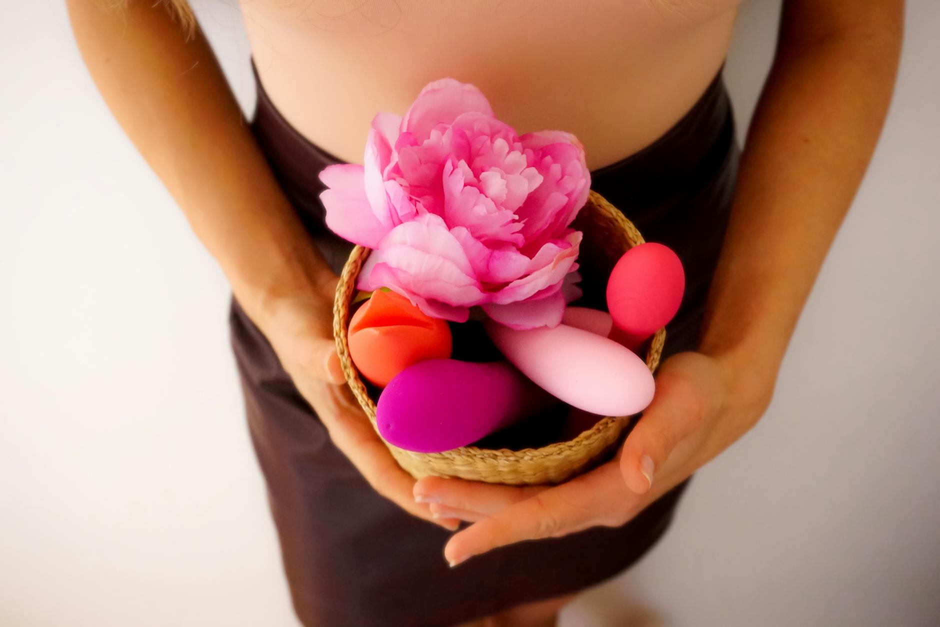 Colorful vibrators and fresh flowers in a basket, symbolizing gentle pleasure and self-care
